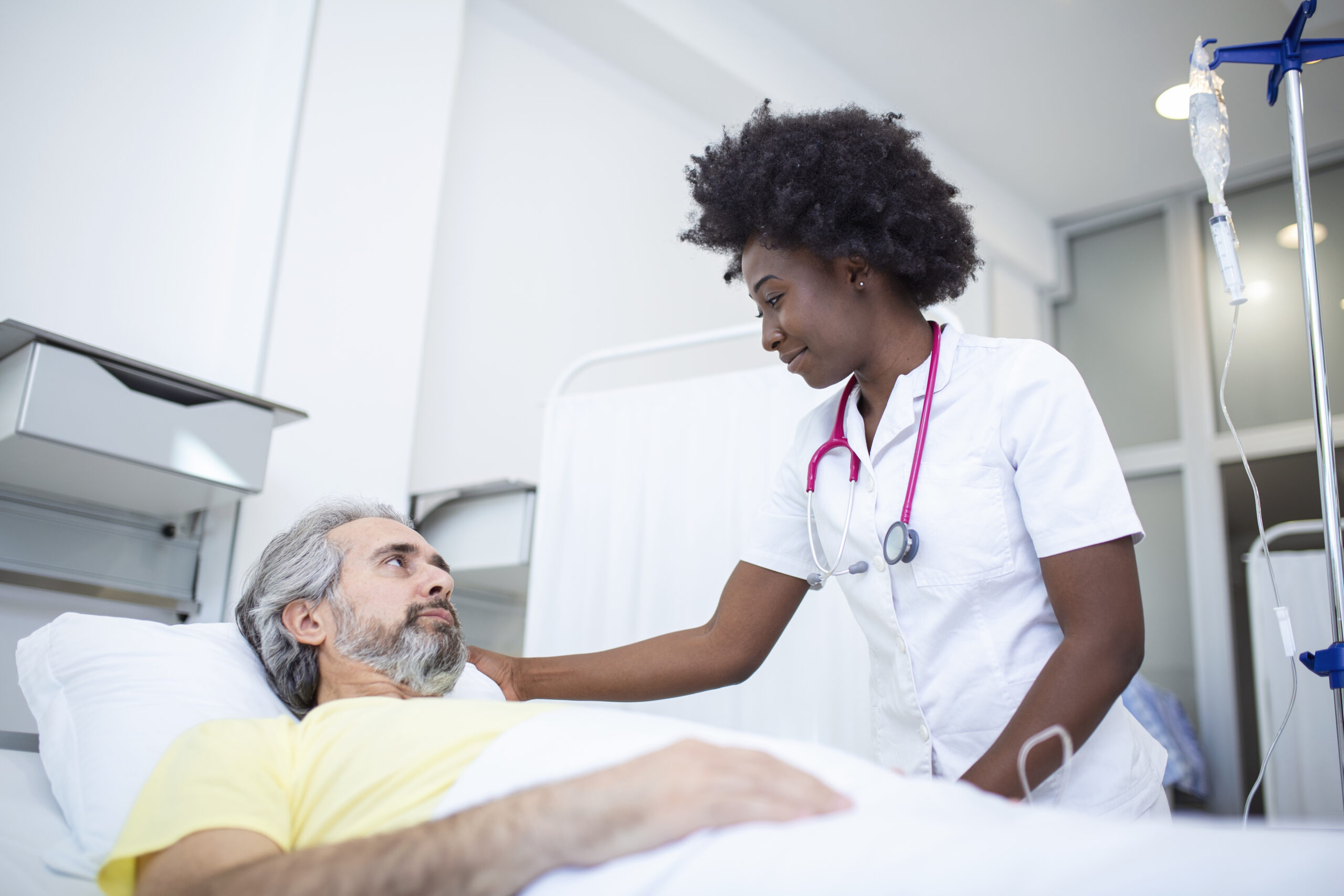 Clinician talking with an older patient in a hospital bed